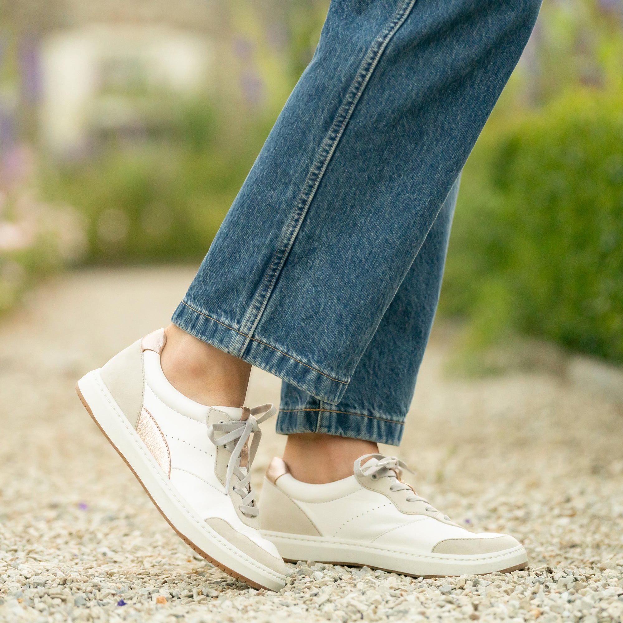 A pair of white leather sneakers with casual accents shown on foot.