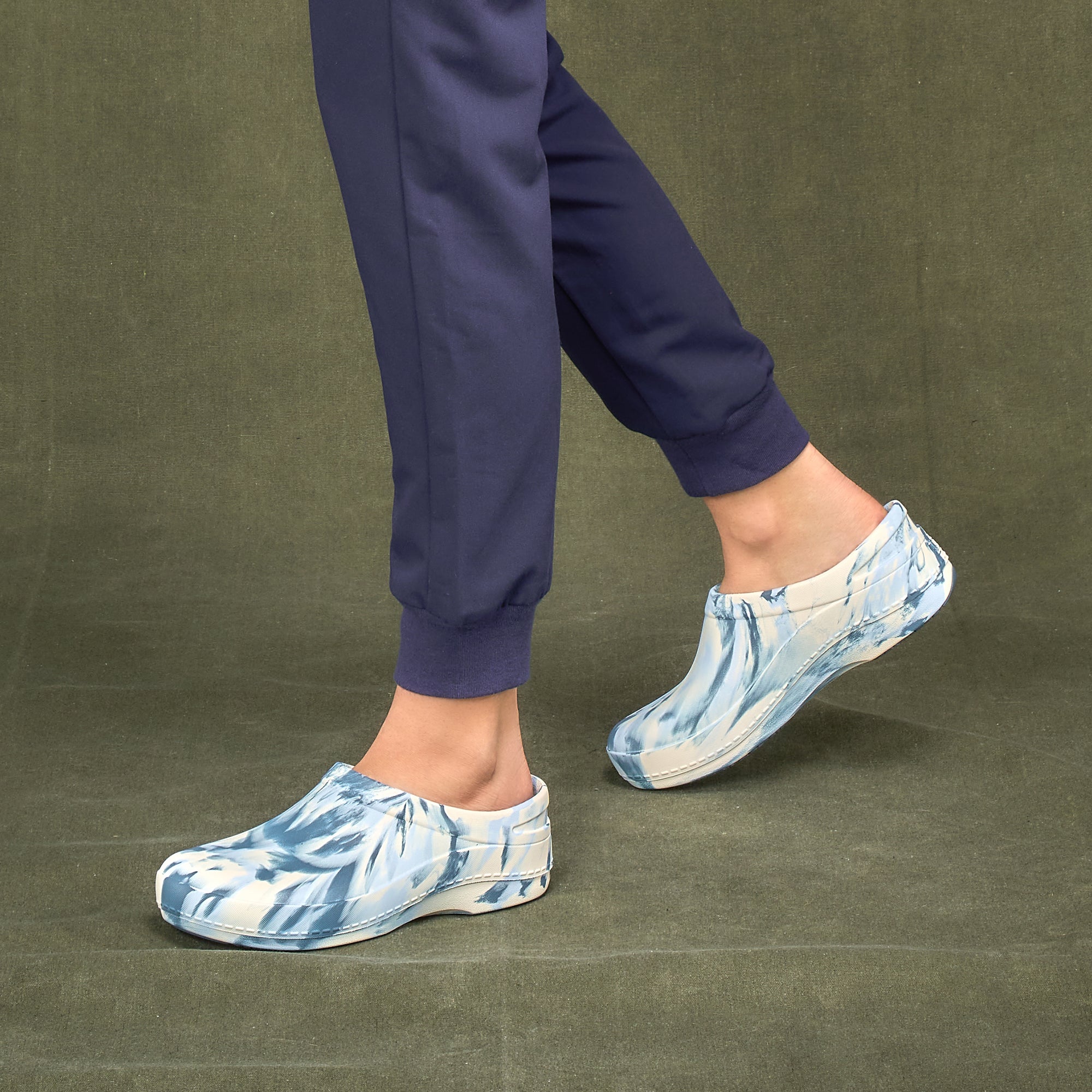 A closeup of a doctor in scrubs wearing blue and white tie-dye molded clogs with slip resistance.