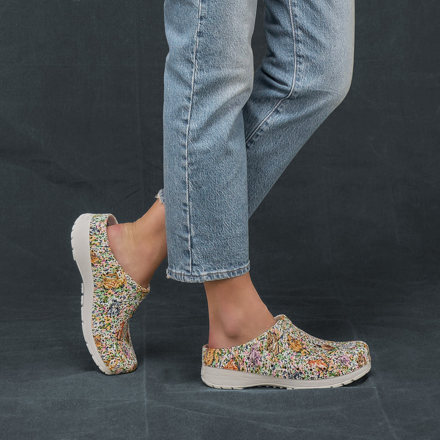 A woman wearing a casual denim outfit with detailed patterned clogs.