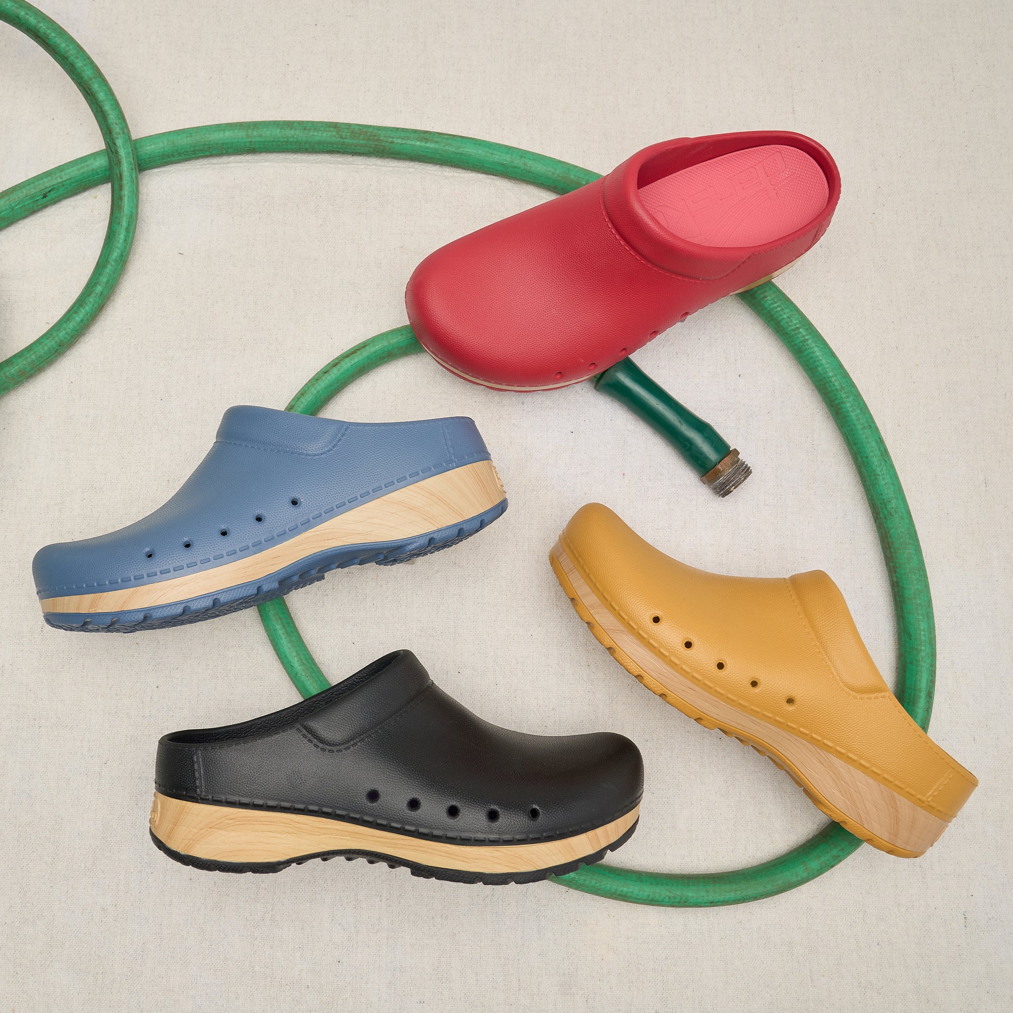 Four colors of a molded clog on and EVA, faux wood sole shown with a hose.