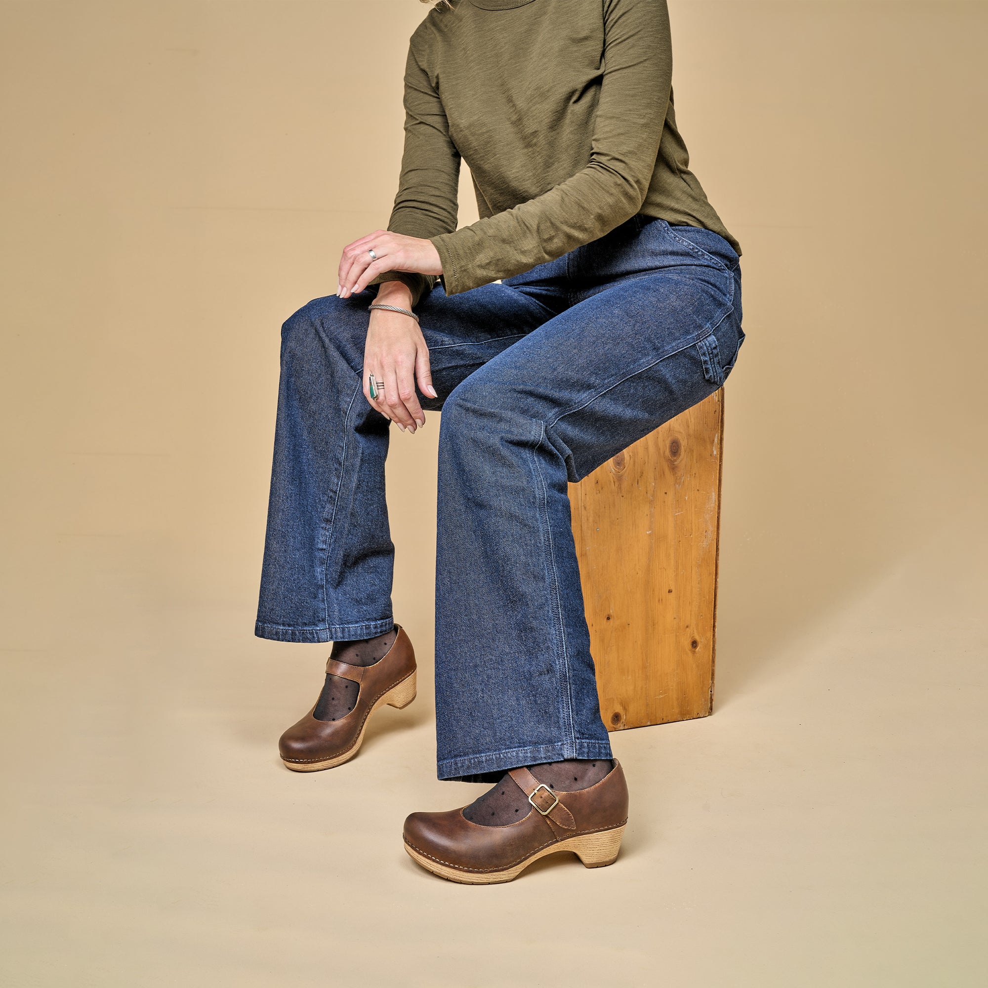 A woman casually styling brown Mary Jane shoes with socks and jeans.