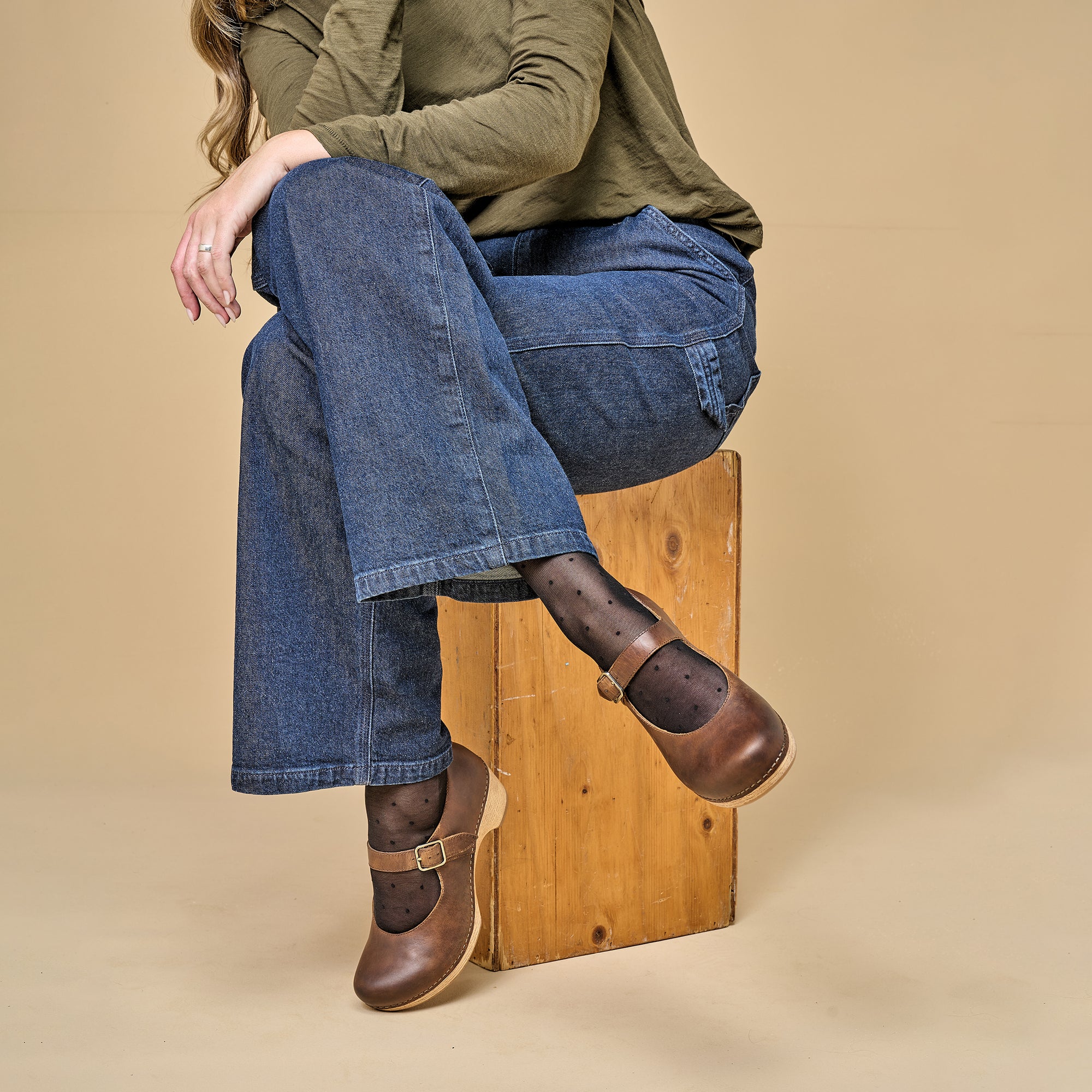 A woman casually styling brown Mary Jane shoes with socks and jeans.