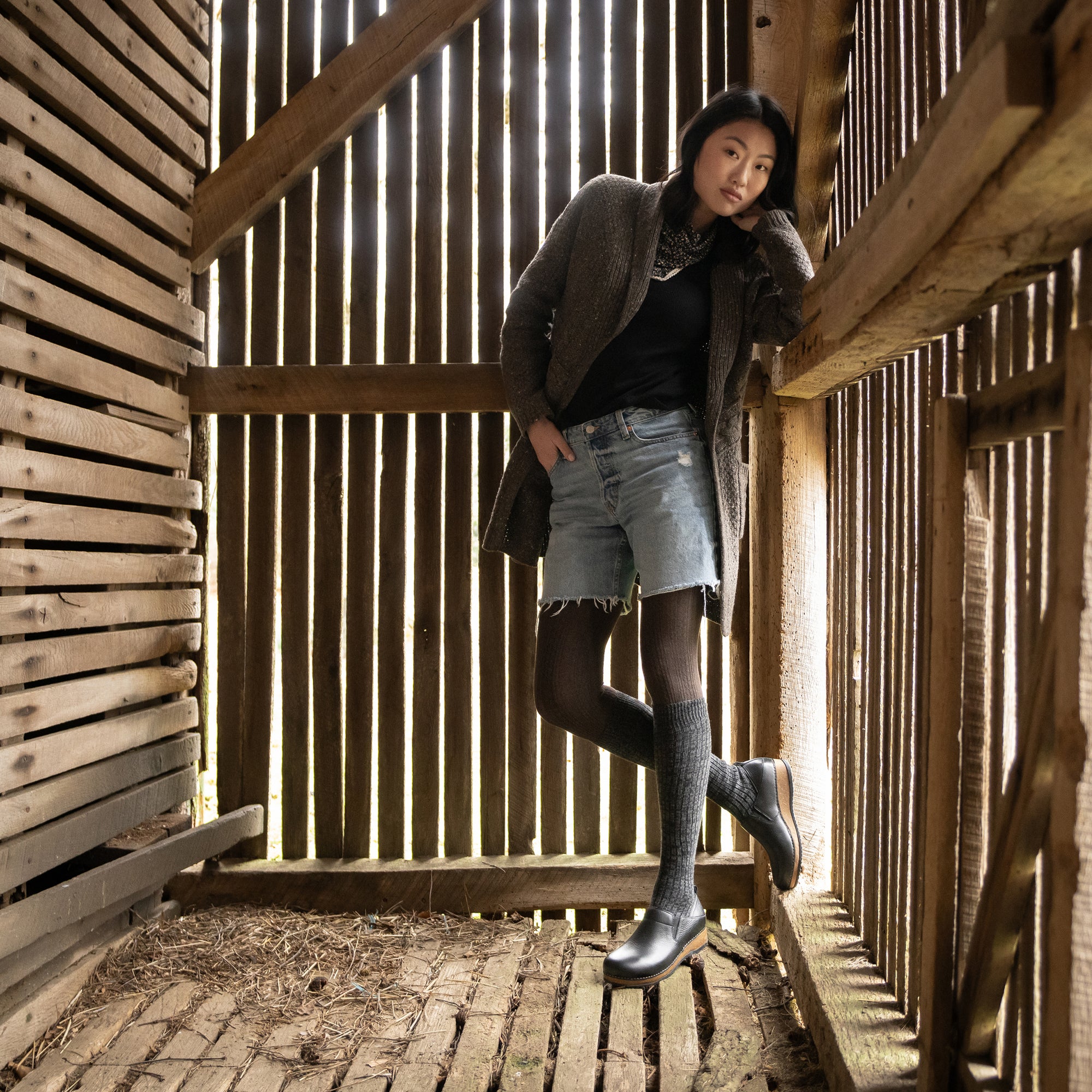 A woman in casual attire wearing black clogs with a cork sole.