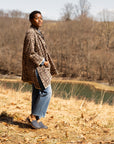 A woman wearing a quilted coat and jeans with blue leather clogs that stand out in a fall field.