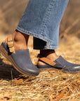 Blue leather clogs with cork soles and a brown leather heel strap shown on foot.