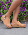Tan clogs with a cork-based sole and heel strap shown on foot.