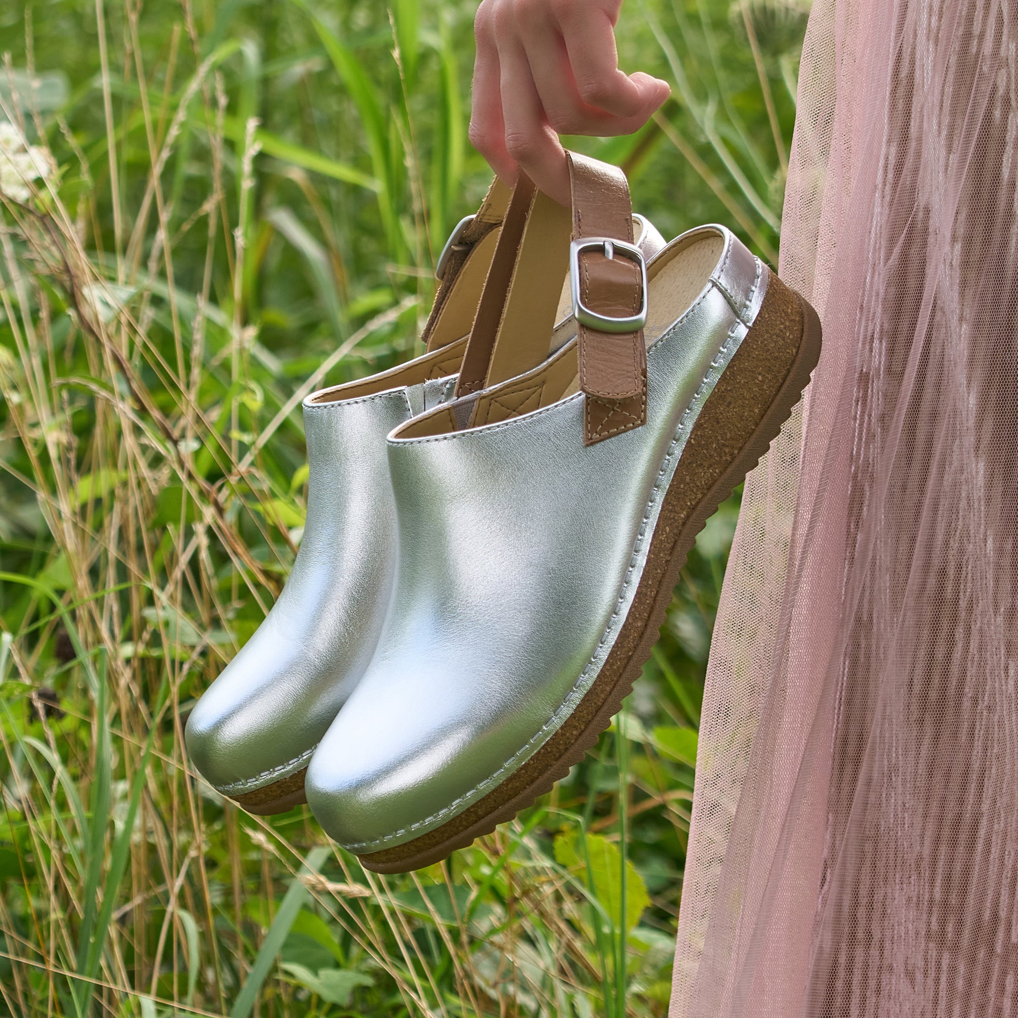 A close-up shot of metallic silver slingback clogs.