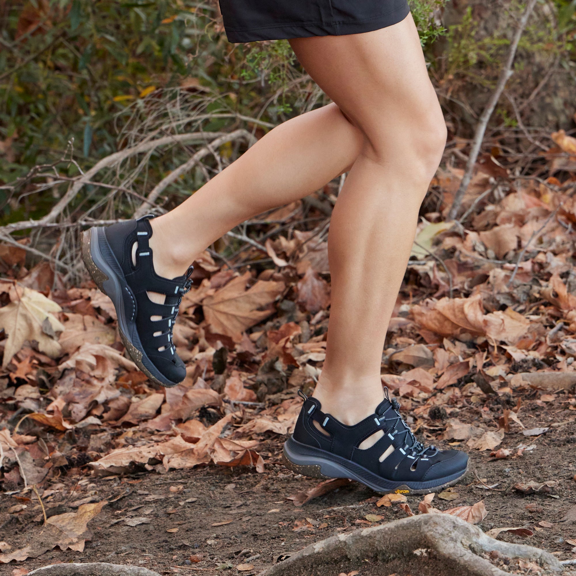 A look at the lightweight and durable black sneaker walking on a path.