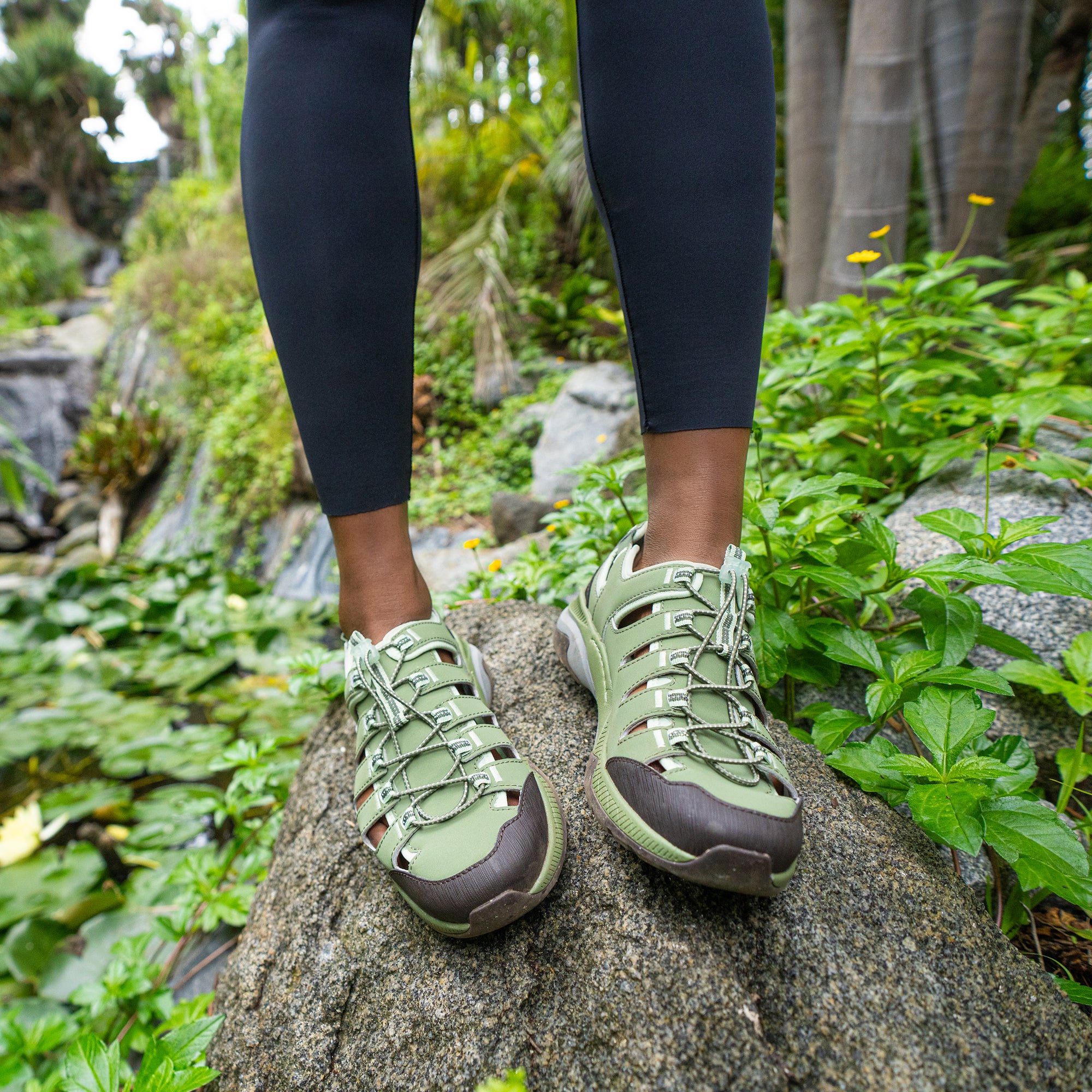 A close shot of lightweight and durable green sneakers standing on a rock.