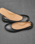 Black ballerina flats showing removable footbed and molded arch support.