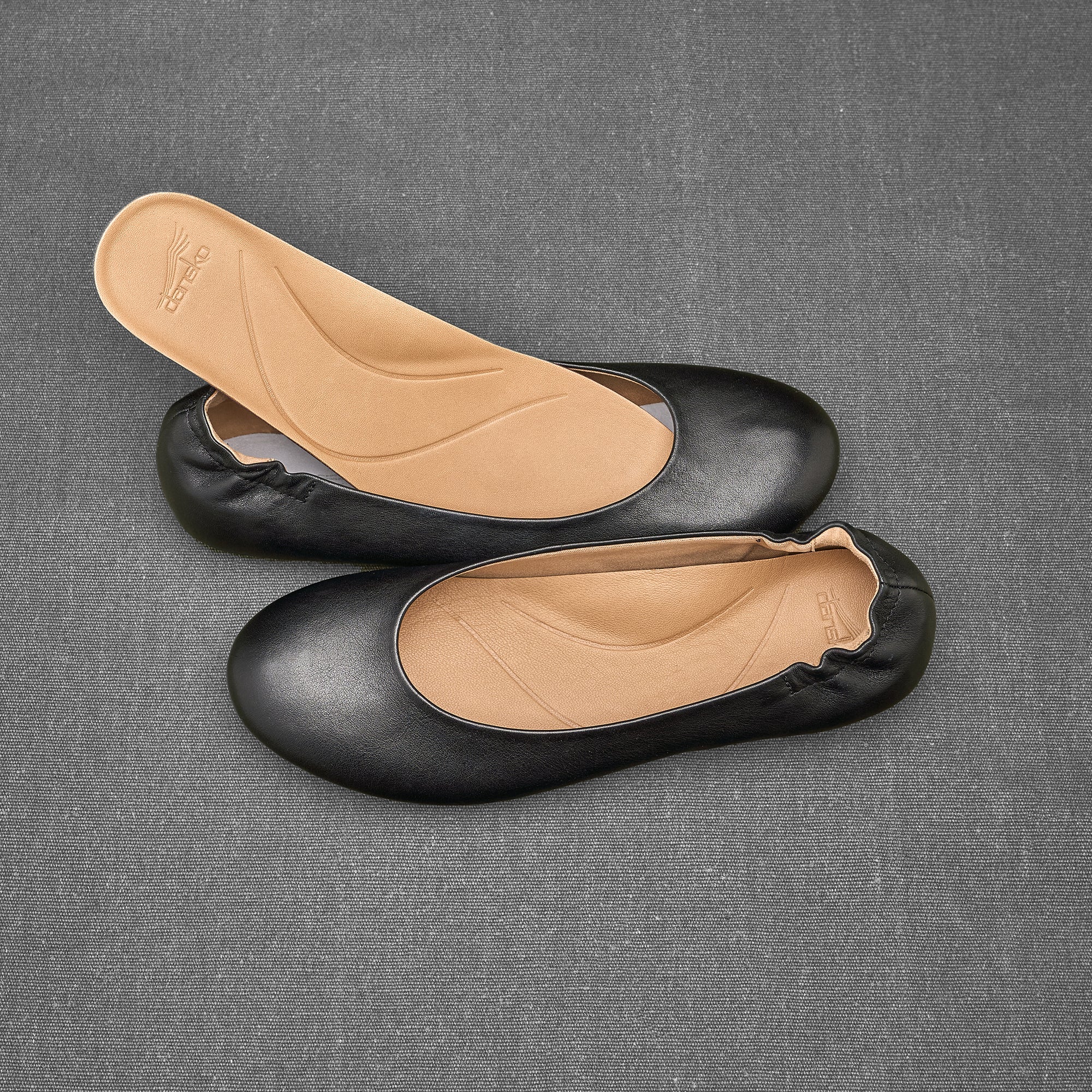 Black ballerina flats showing removable footbed and molded arch support.