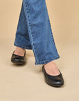 A closeup of black ballerina flats shown on foot.