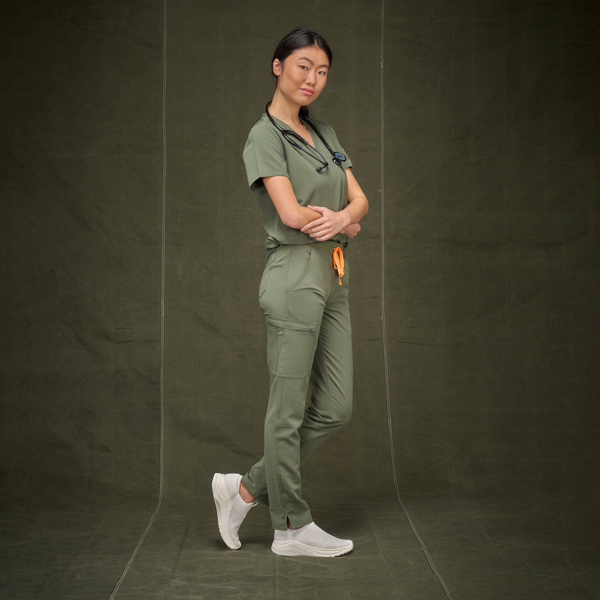 A nurse in green scrubs shown in easy-wear white sneakers.