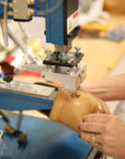 A machine personalizing a pair of clogs with a dog paw.