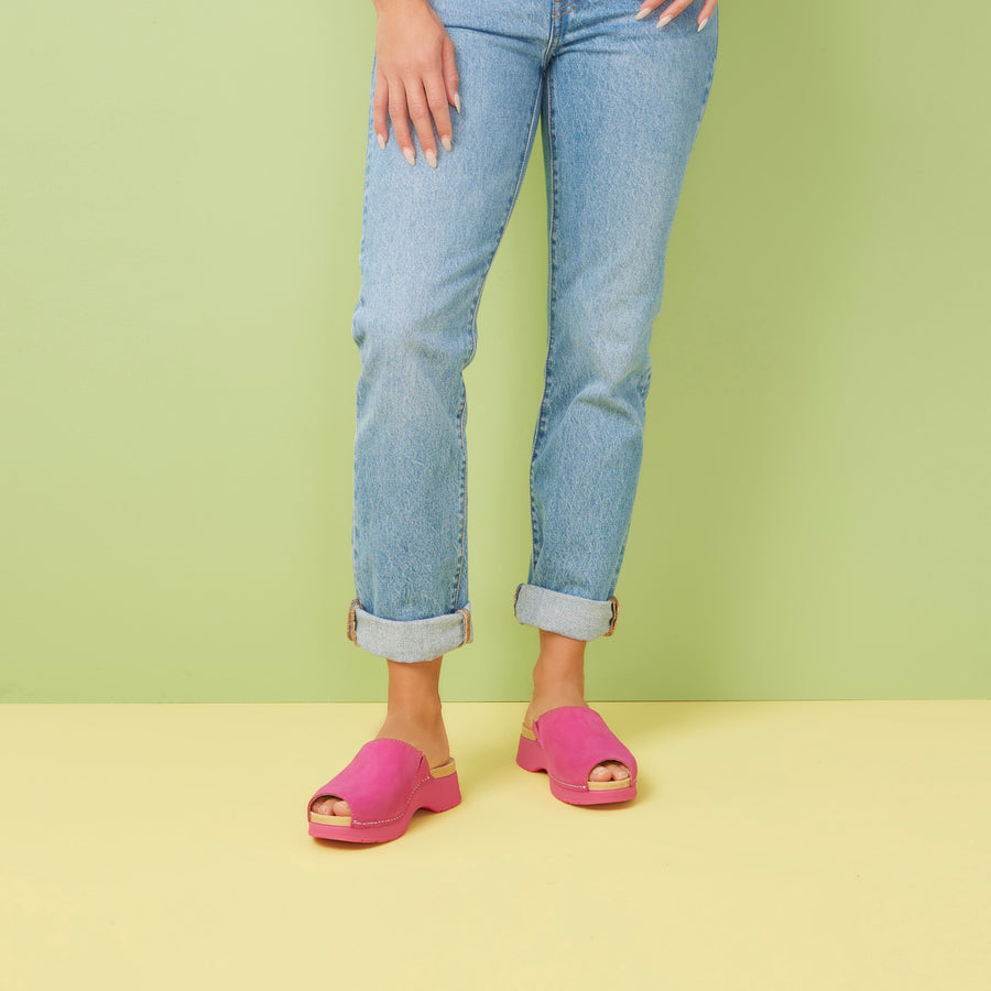 A woman wearing jeans and fuchsia slide sandals to add a splash of color.