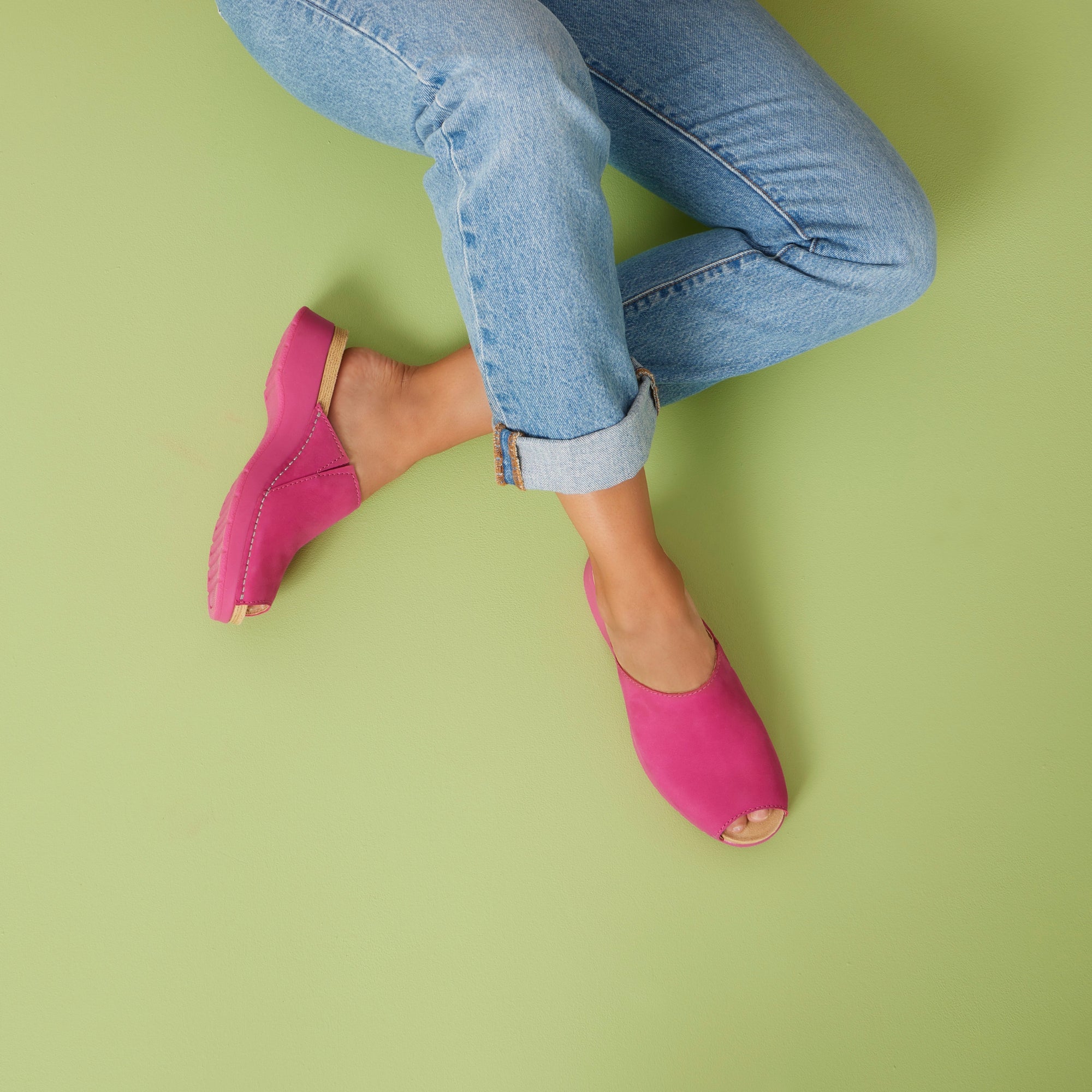 Fuchsia slide sandals shown on a subtle green background to show the pop of color.