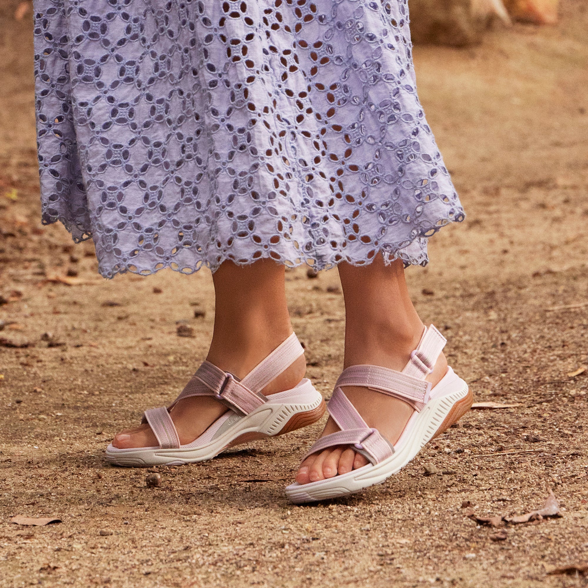 A close shot of pink and white walking sandals on a dirt path.
