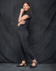 A woman in a dark casual outfit in black waxy transitional sandals.