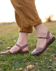A closeup shot in a field of brown waxy leather transitional sandals.
