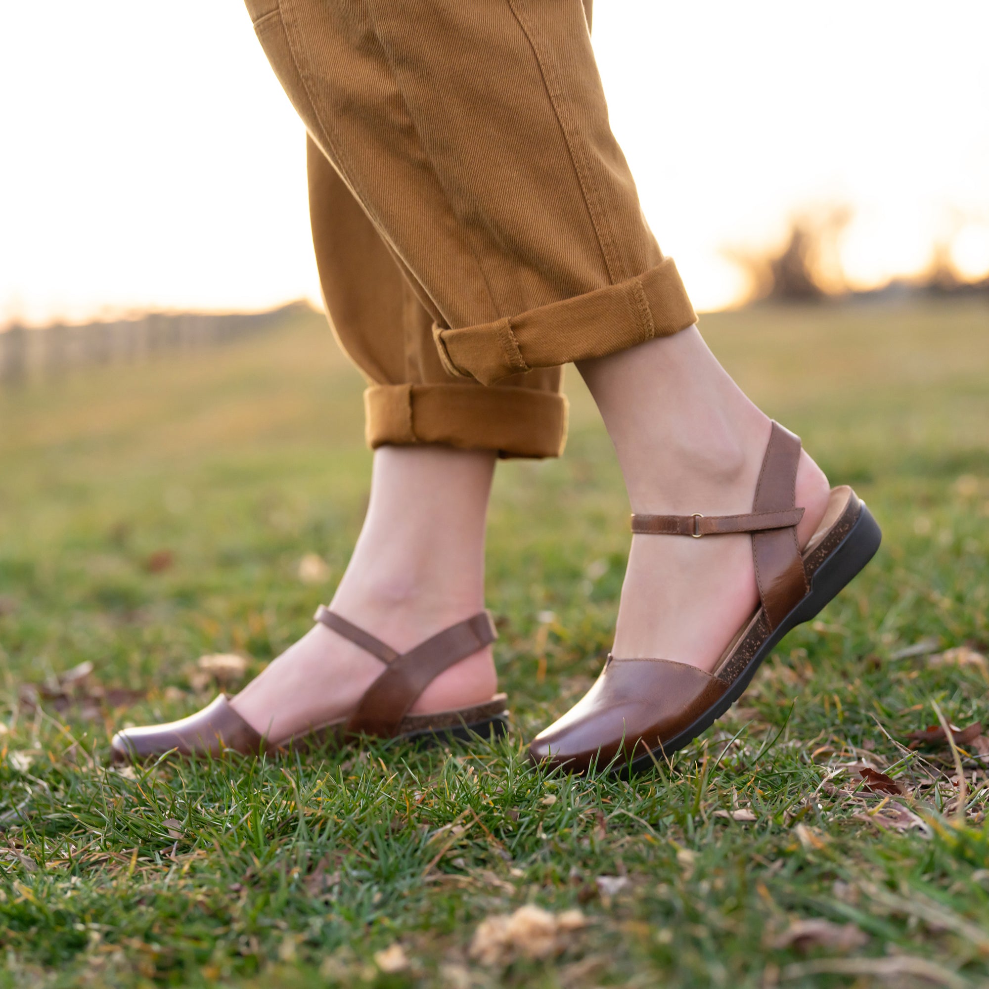 A closeup shot in a field of brown waxy leather transitional sandals.