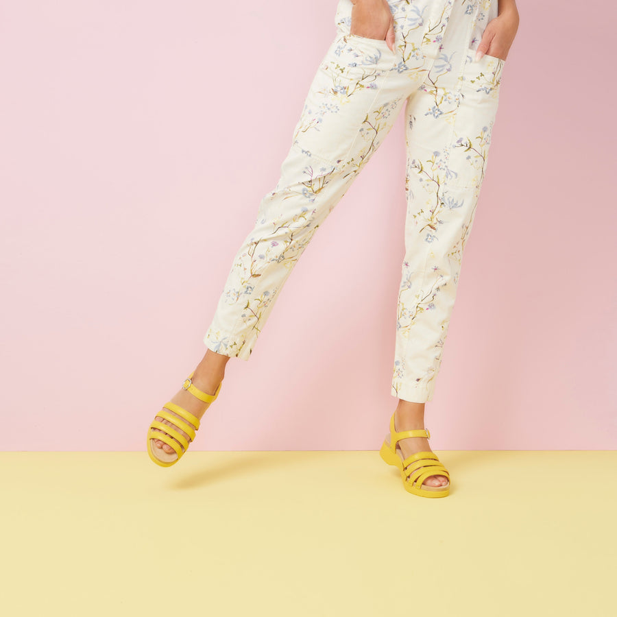 A woman in beautiful white pants and vibrant yellow sandals.