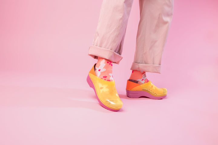 Yellow translucent clogs worn with pink pants and flowery socks.