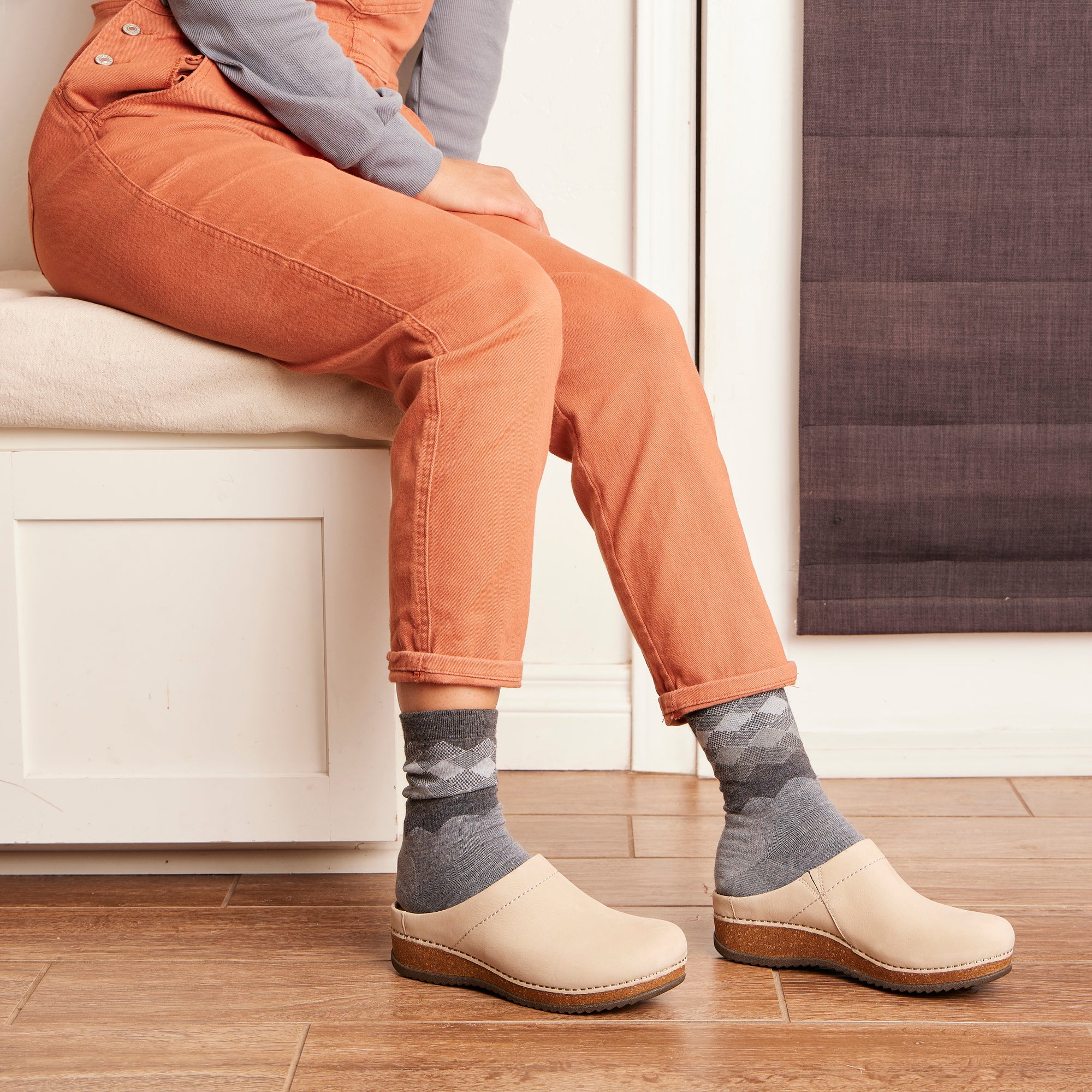 A cozy outfit with patterned socks and light tan mule clogs that have a cork-based outsole.