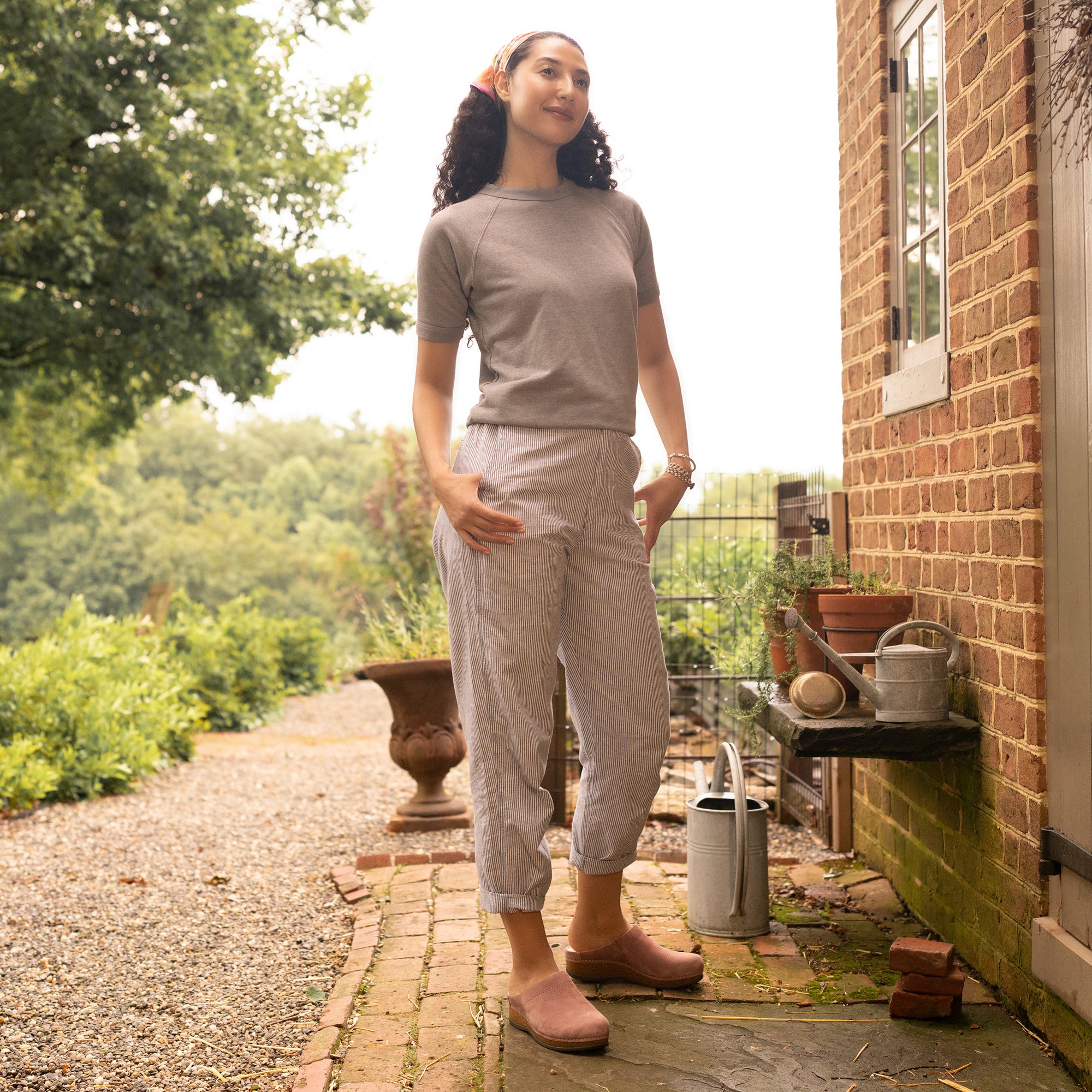 A woman in a comfortable outfit including light pink mule clogs.