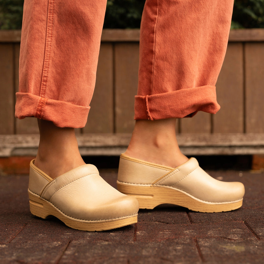 Light tan clogs with wood patterned outsoles worn with fun orange jeans.