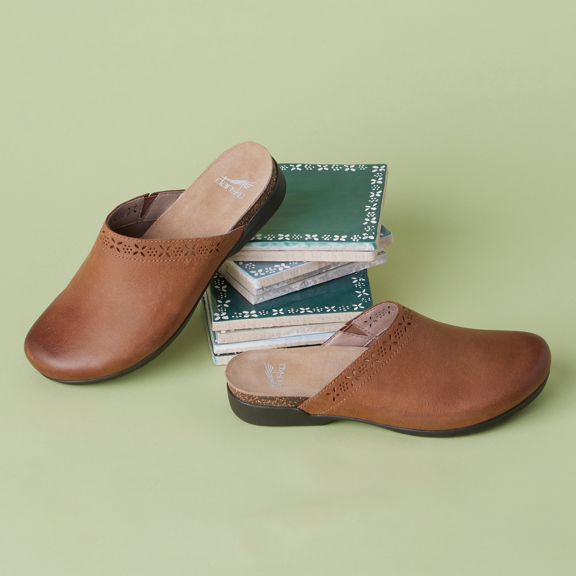 Brown leather slip-on mule shown with printed detail that appears on the uppers.