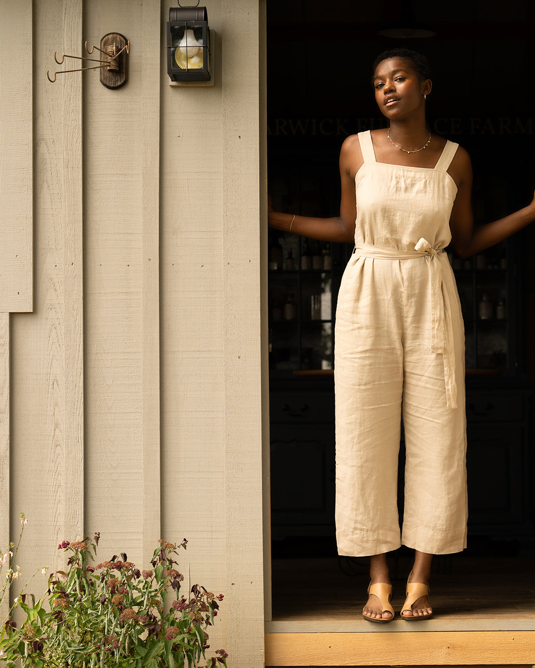 Girl in neutral jumpsuit wearing honey sandals.