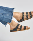 Close up of strappy black flat sandal.