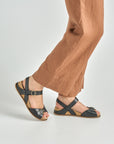 Close up of black flat ankle strap sandals.