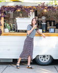 A woman ordering a drink and wearing a casual outfit stands on black flatform sandals with a unique strap design.