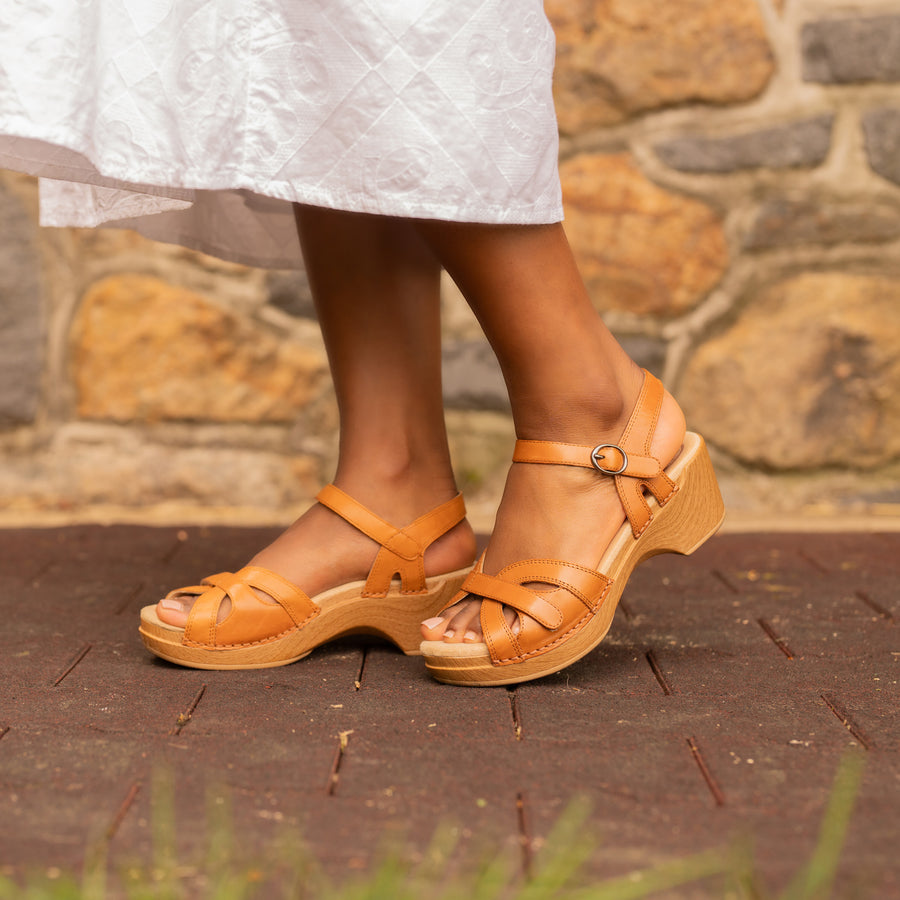 A closeup on brown flatform sandals with a unique strappy design.