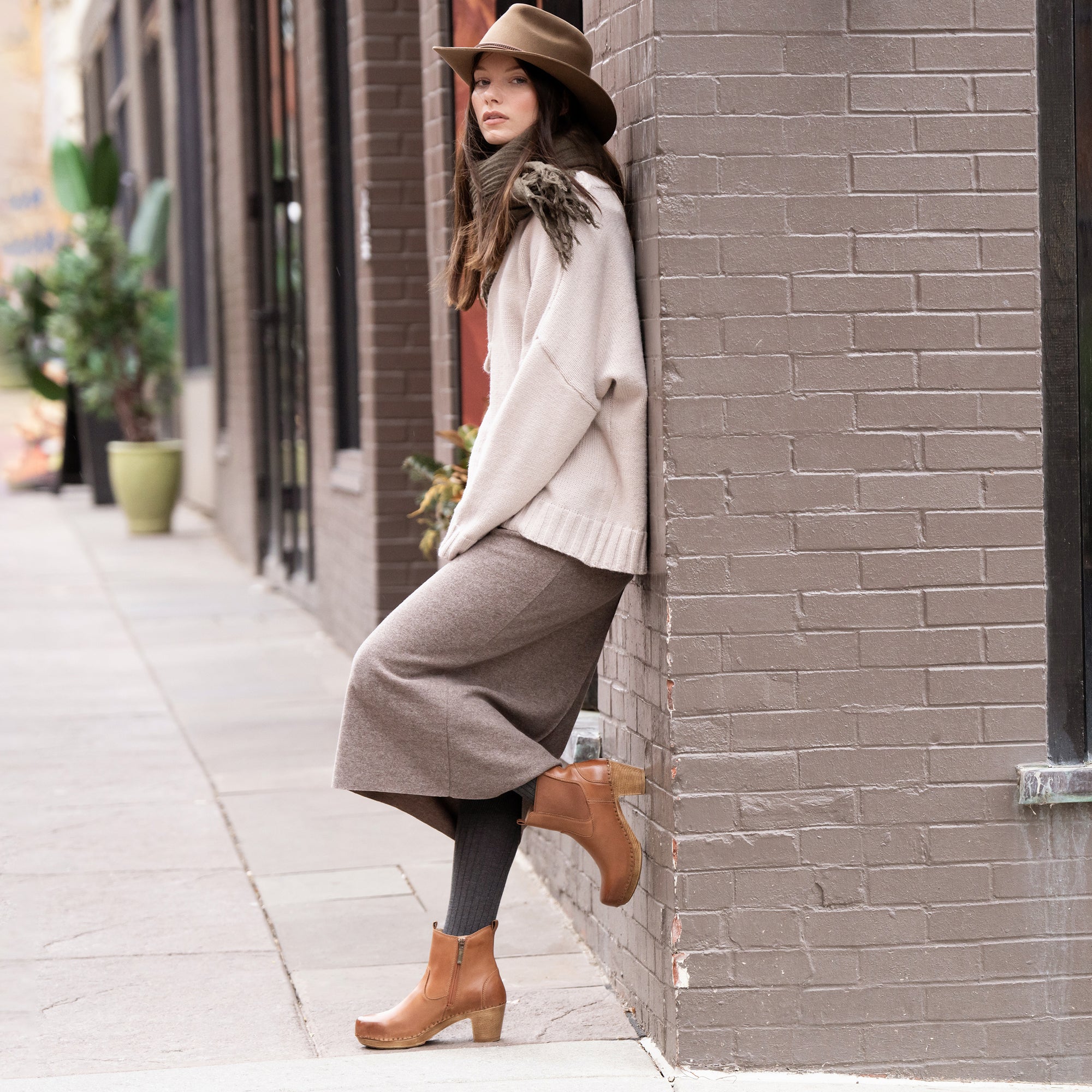 A woman in town wearing fashionable fall attire and brown heeled boots.