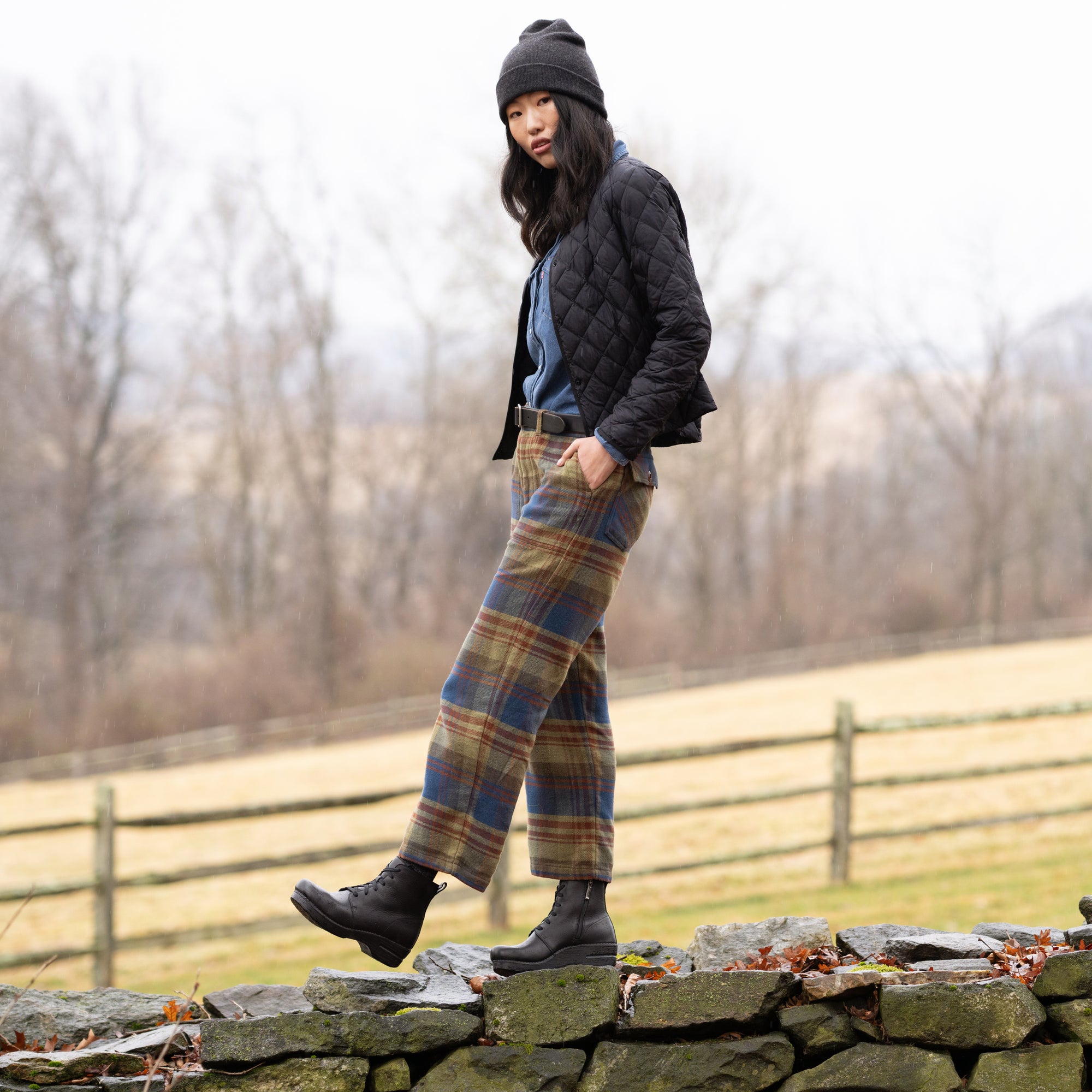 A woman wearing plaid pants and black combat booties with winter attire.