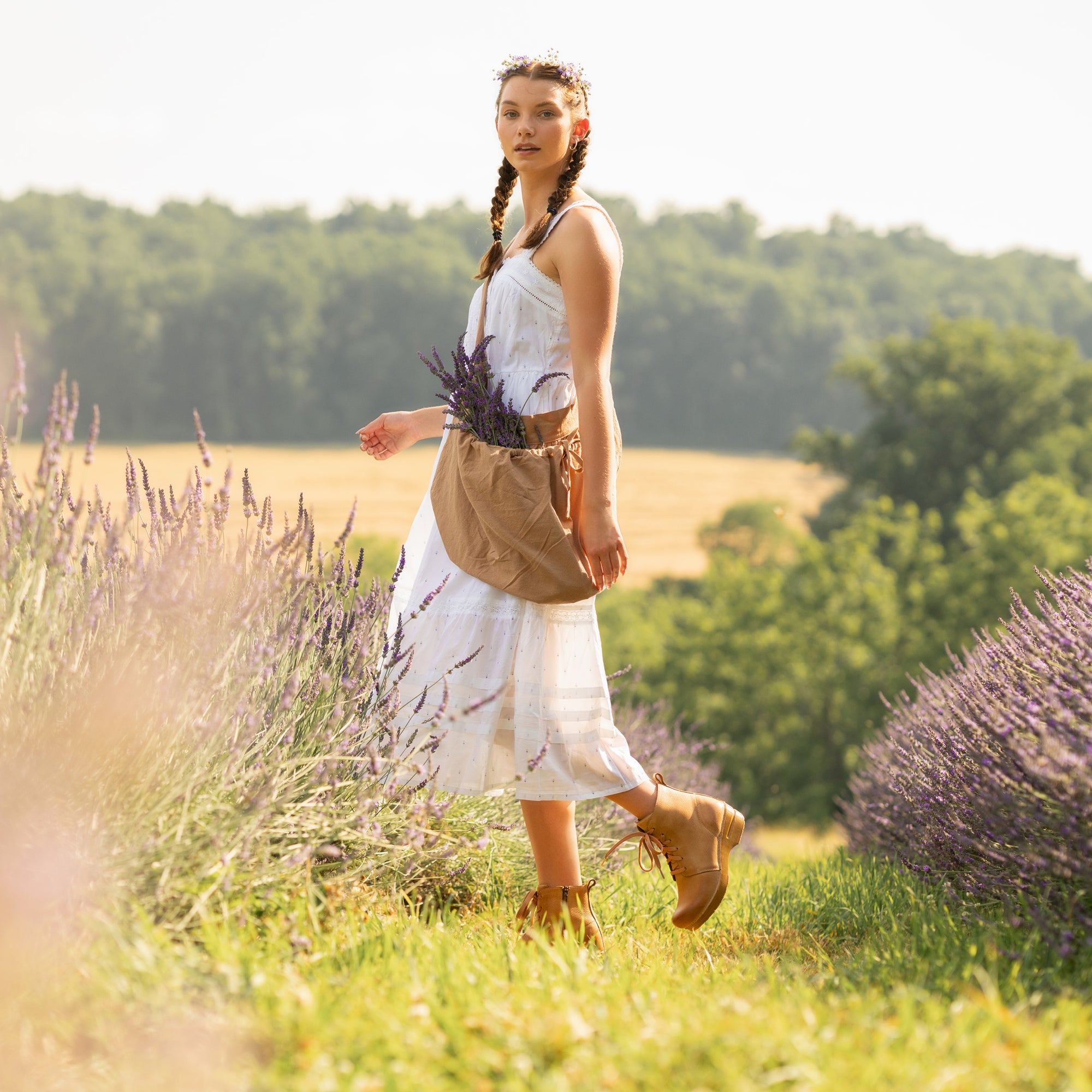 A woman in a lavender field wearing a white dress with tan combat booties