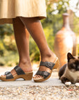 A closeup on black two-strap sandals and a cat.
