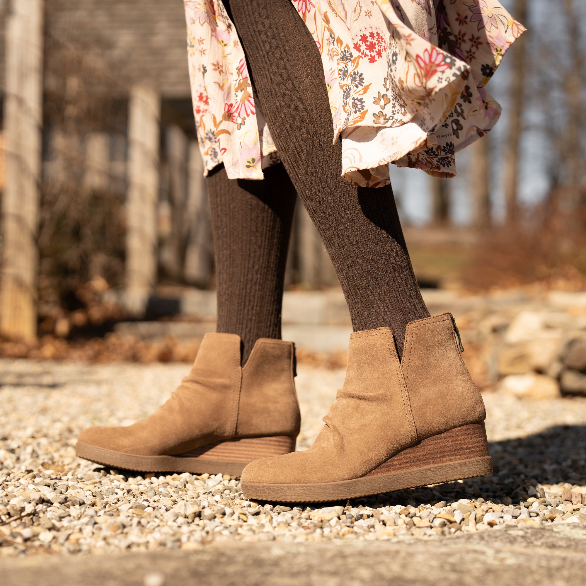 An on-foot shot of brown wedge booties shown with brown stockings.