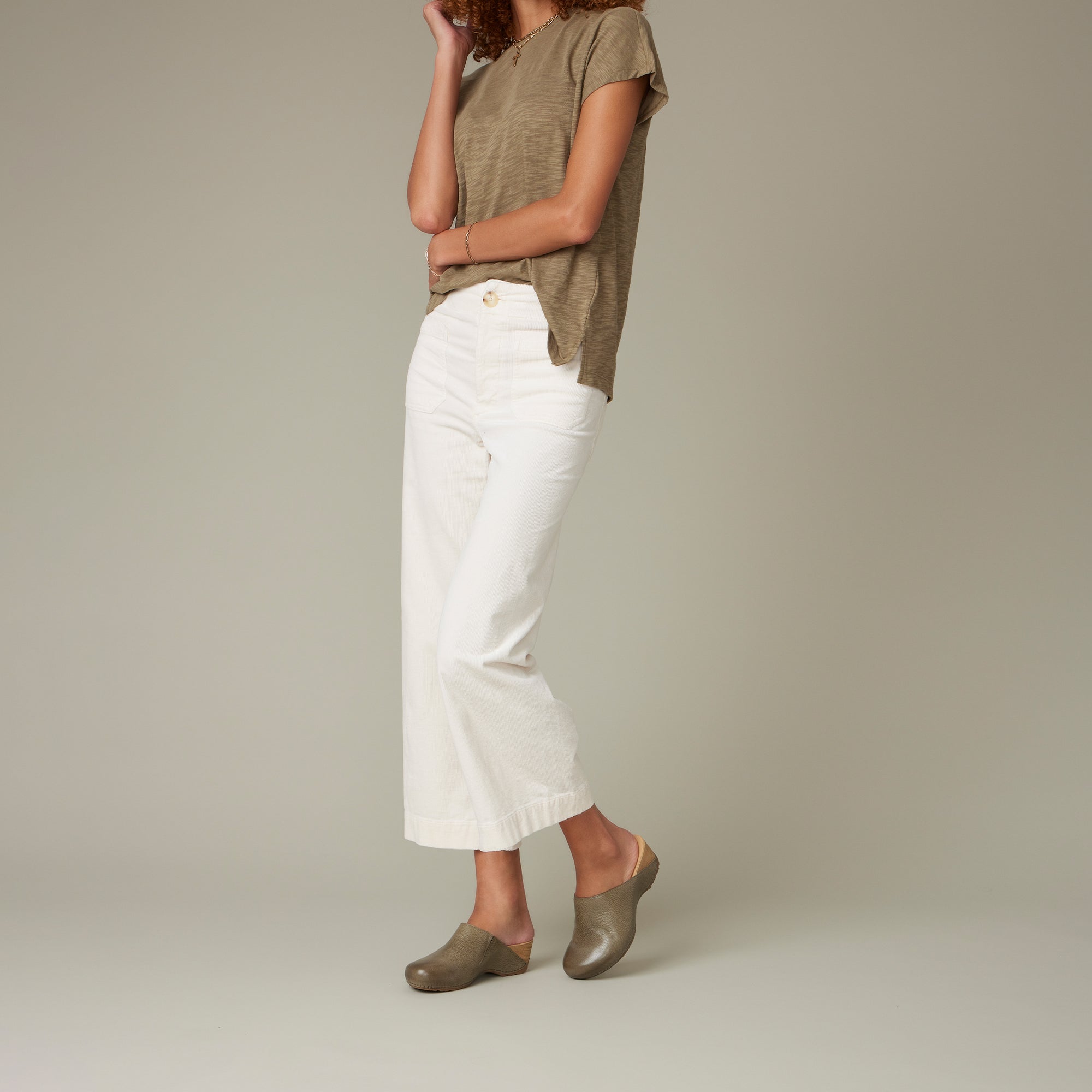 A woman in casual attire wearing slide clogs in a neutral earthtone.