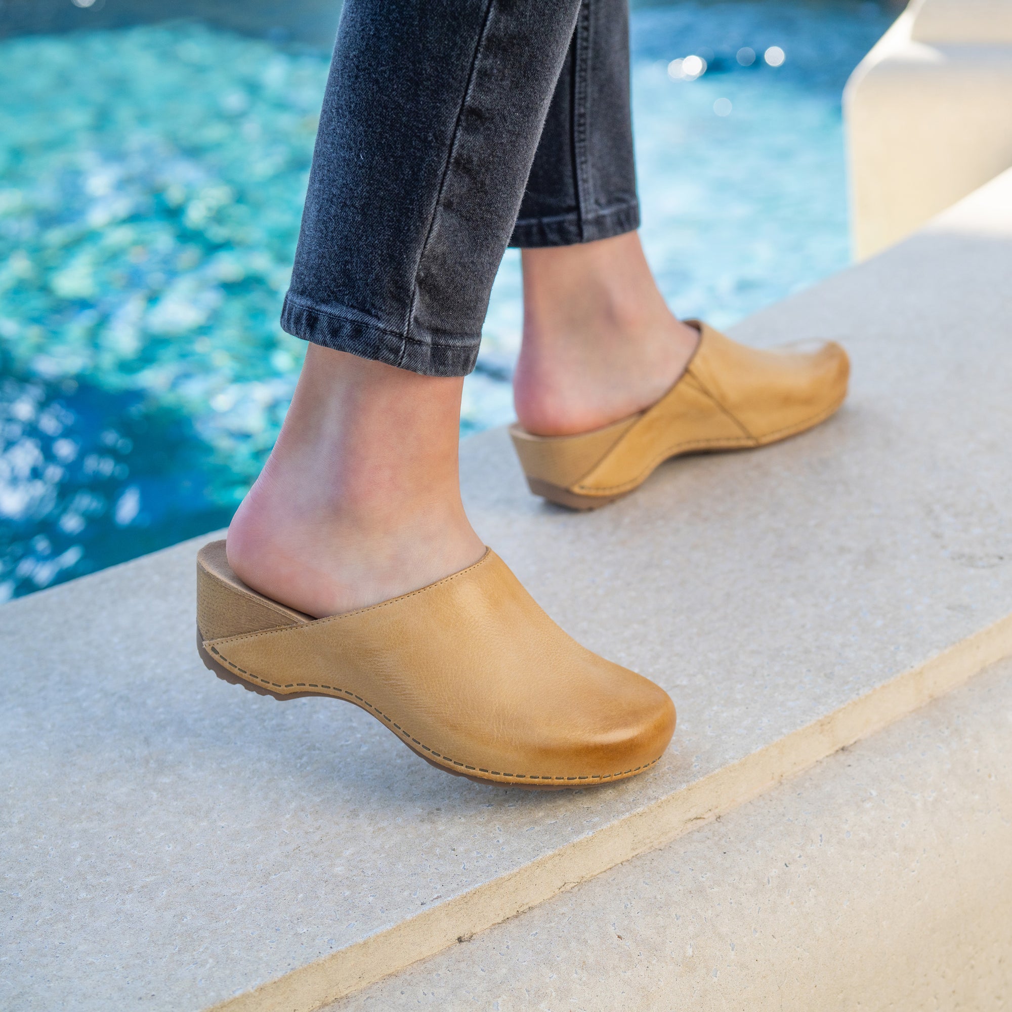 A closeup of backless tan leather clogs.