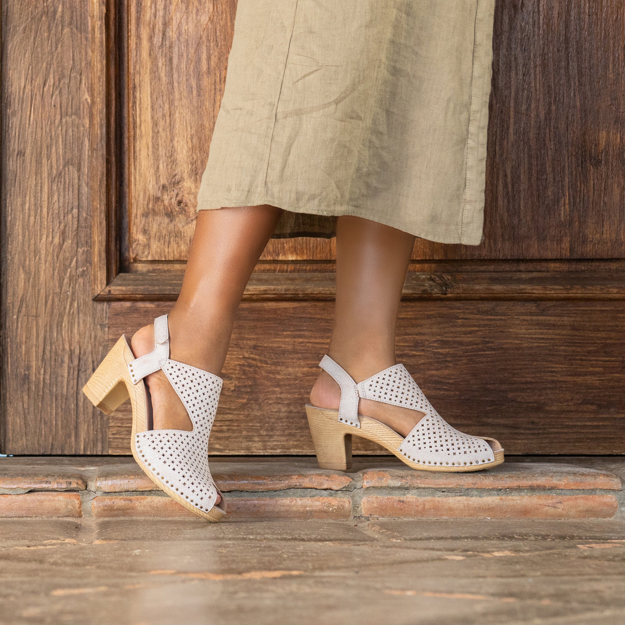 White heeled sandals with a peep toe construction and cutout design on the leather uppers.