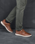 Man in grey chinos wearing trendy and stylish brown leather sneakers.