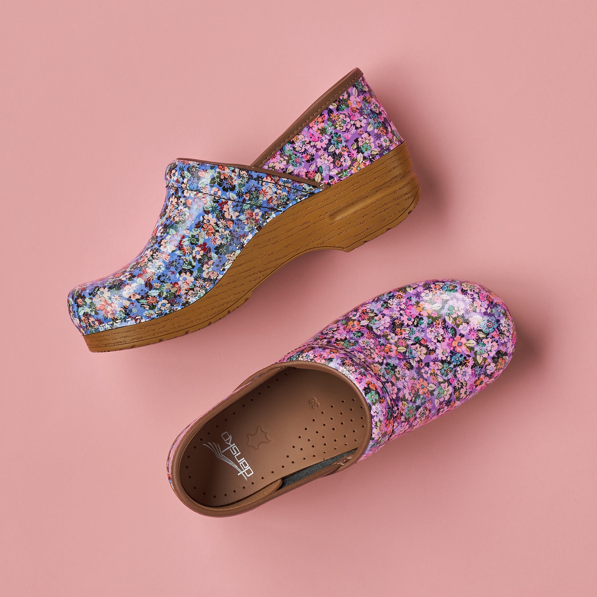 Mismatched floral print clogs shown on a light pink background.