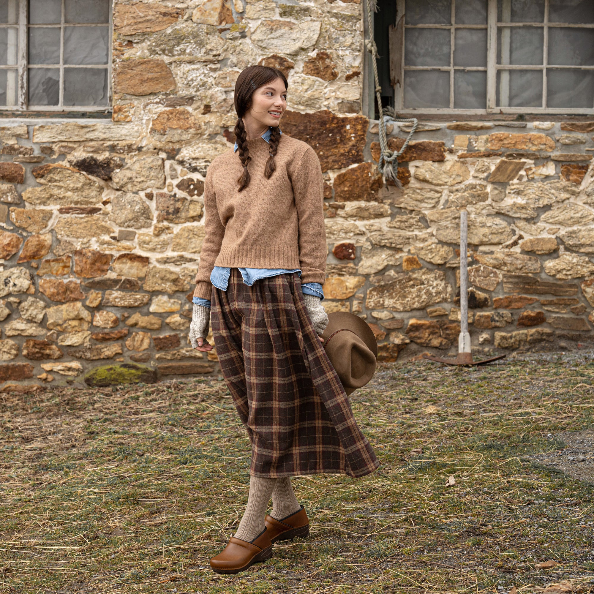 A girl dressed for colder weather wearing rich caramel clogs.