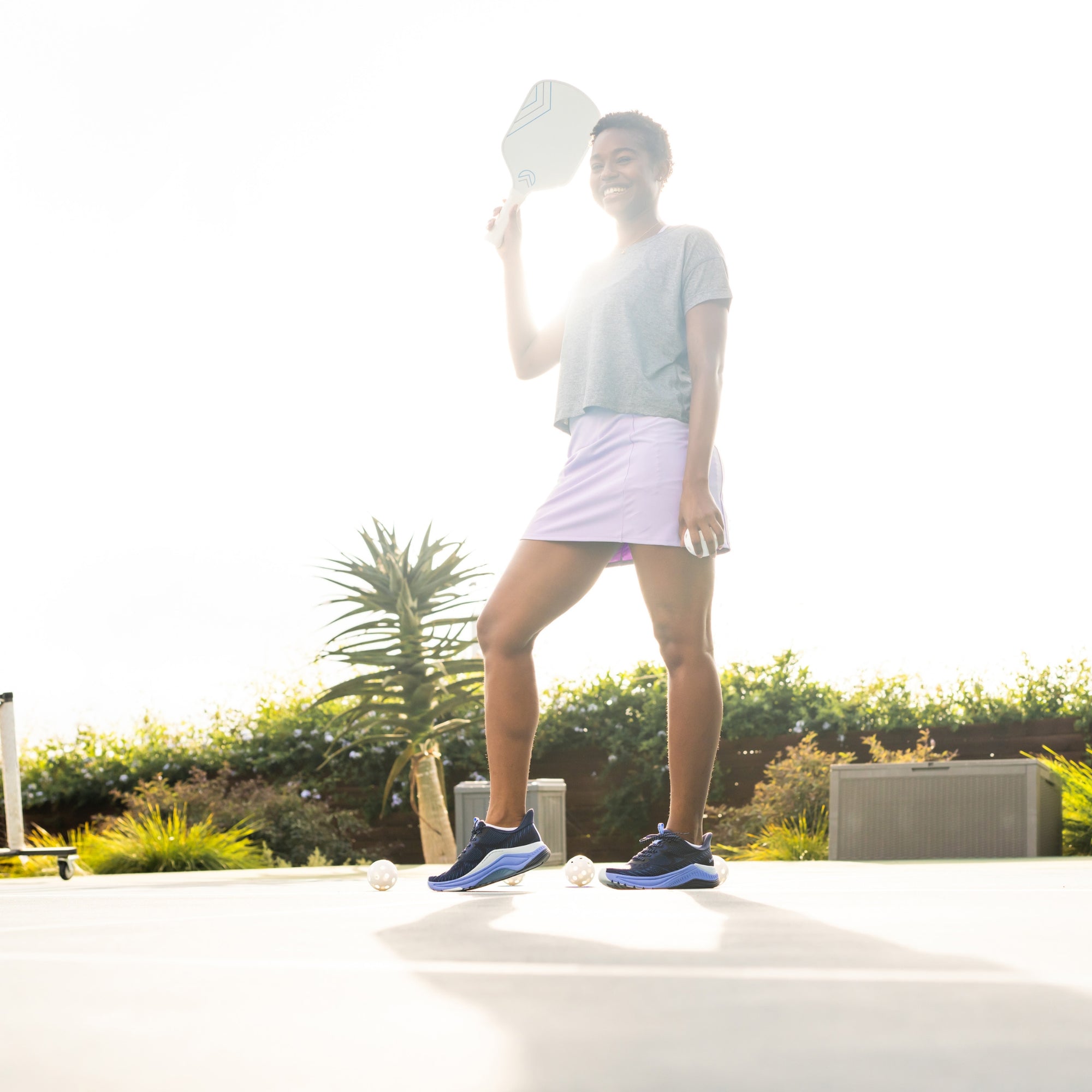 A woman playing pickleball in stylish activewear and navy blue active sneakers. 