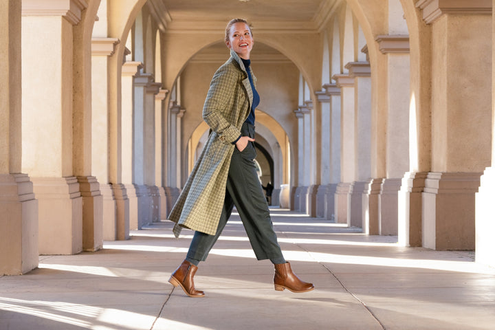 A stylish woman walking through a courtyard in beautiful brown booties with a perfect heel height.