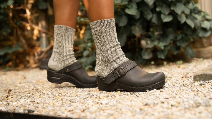 Close up of black slingback clogs worn with thick gray wool socks.