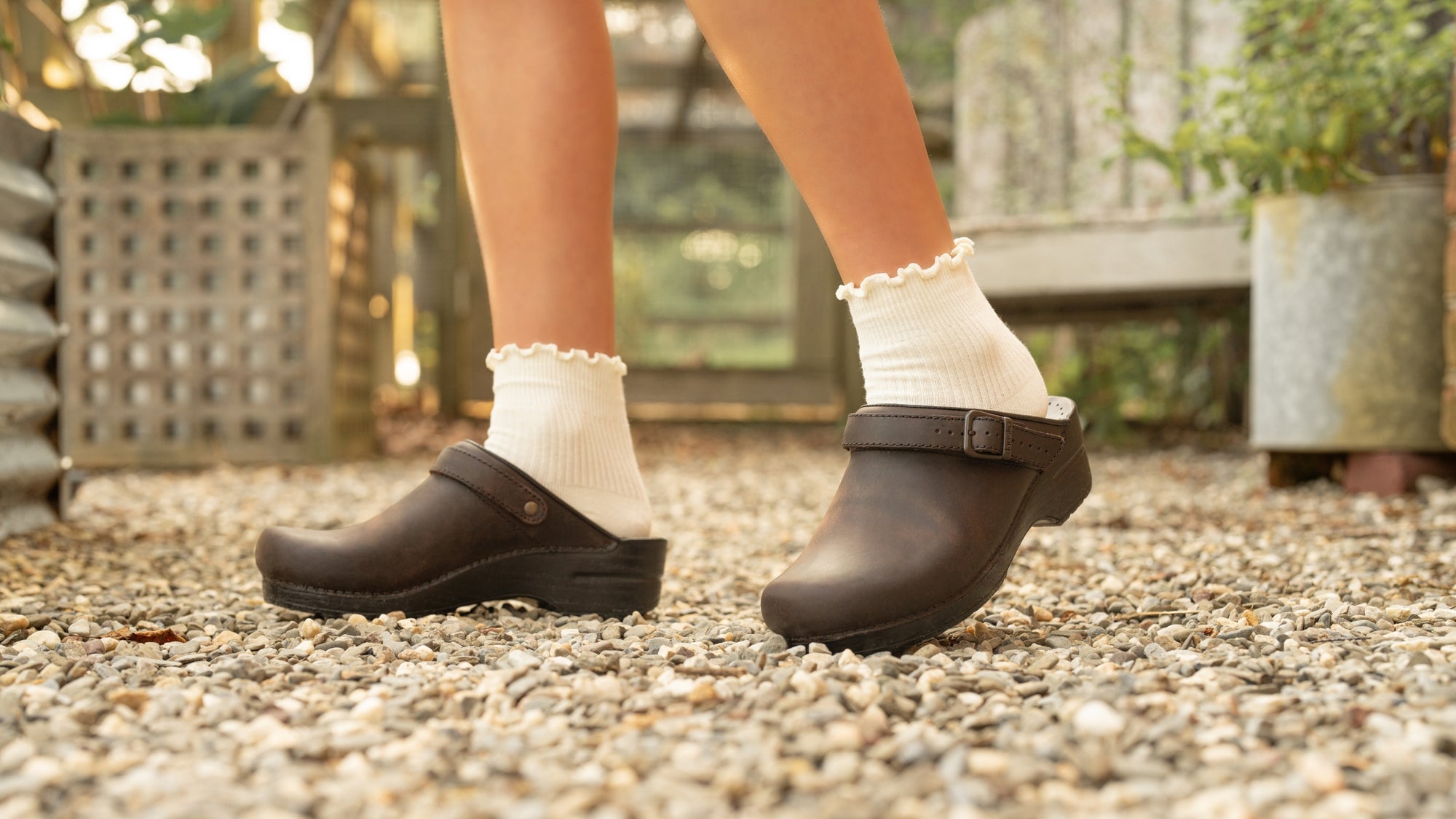 Close up of brown slingback clogs worn with frilled socks.